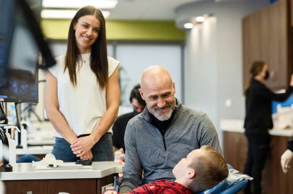 Orthodontist speaking with young patient while mother stands nearby